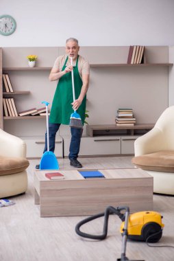 Yaşlı müteahhit evi temizliyor.