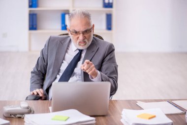 Old businessman employee unhappy with excessive work at workplace