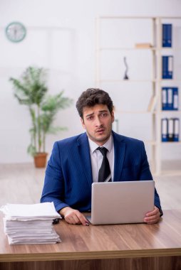 Young employee and too much work at workplace