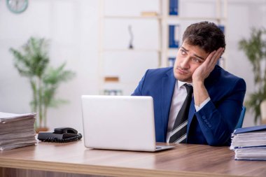 Young employee and too much work at workplace