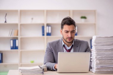 Young employee and too much work at workplace