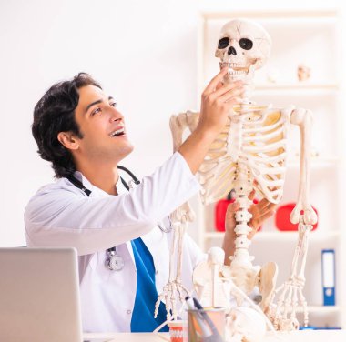 İskeleti olan genç erkek doktor.