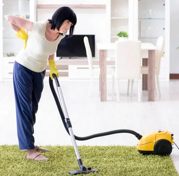 Yaşlı yaşlı kadın elektrik süpürgesinden sonra yoruldu.