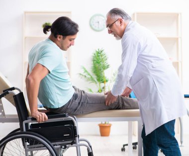 Tekerlekli sandalyedeki erkek hasta yaşlı doktoru ziyaret ediyor.