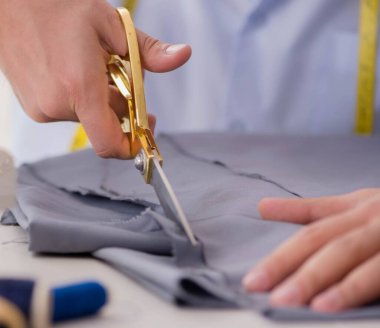 Genç terzi yeni elbiseler üzerinde çalışıyor.