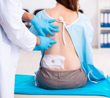 Yaralı genç kadın erkek doktoru ziyaret ediyor.