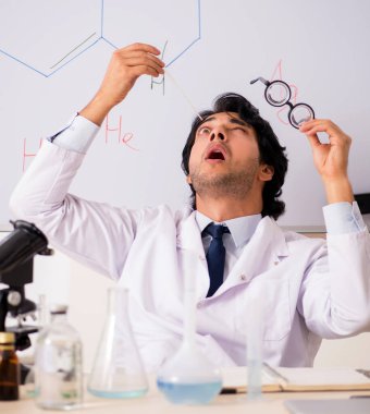 Beyaz panonun önündeki komik genç kimyager.