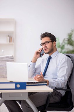 Young employee and too much work at workplace