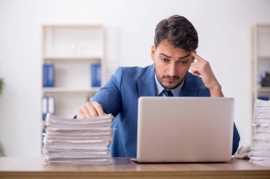 Young employee and too much work at workplace