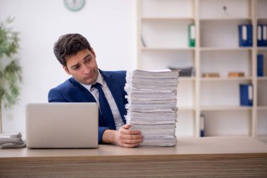 Young employee and too much work at workplace