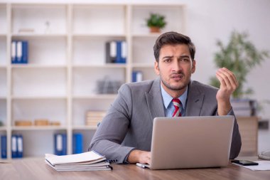 Genç işadamı işyerinde oturuyor.