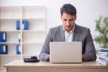 Young employee and too much work at workplace