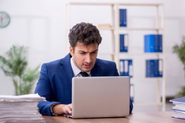 Young employee and too much work at workplace