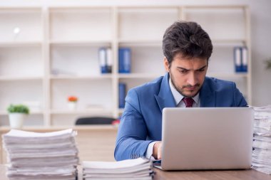 Young employee and too much work at workplace