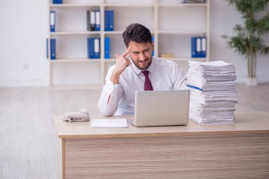 Young employee and too much work at workplace