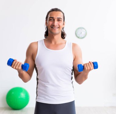 Genç yakışıklı adam içeride spor egzersizleri yapıyor.