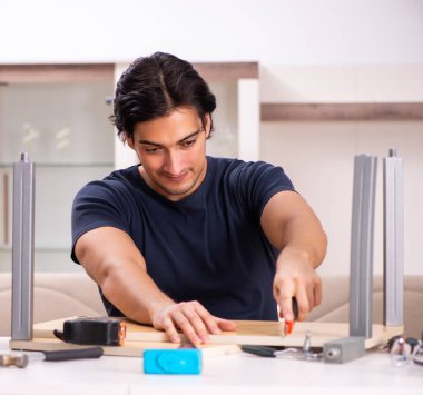 Evde mobilya tamir eden genç adam.