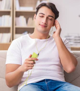 Kanepede oturmuş müzik dinleyen adam.