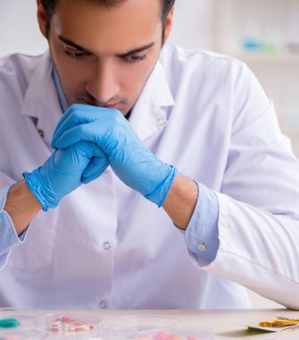 Uyuşturucu sentezi konseptinde genç erkek laboratuvar asistanı