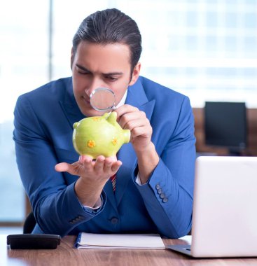 Genç yakışıklı işadamı ofiste oturuyor.