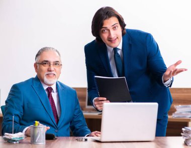 Genç ve yaşlı çalışanlar ofiste birlikte çalışıyorlar.