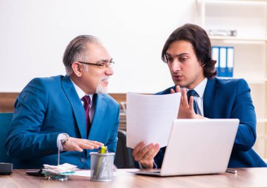 Genç ve yaşlı çalışanlar ofiste birlikte çalışıyorlar.