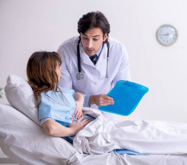 Erkek doktor koğuştaki kadın hastayı ziyaret ediyor.