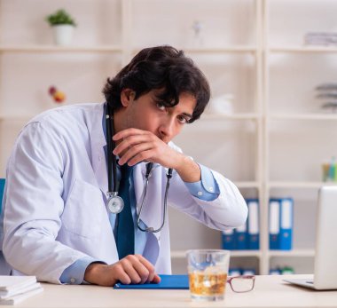 Ofiste içen genç erkek doktor.