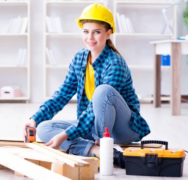 Tamirci kadın marangoz, ahşap döşemeleri onarım için kesiyor.