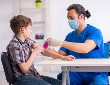 Genç çocuk hastanede doktoru ziyaret ediyor.