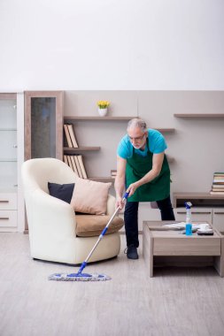 Yaşlı müteahhit evi temizliyor.