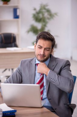 Genç işadamı işyerinde oturuyor.