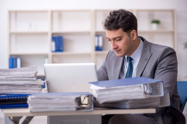 Young employee and too much work at workplace