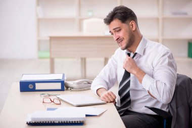 Genç işadamı işyerinde oturuyor.