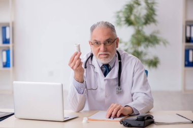 Old doctor suggesting pills at the hospital