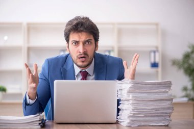 Young employee and too much work at workplace