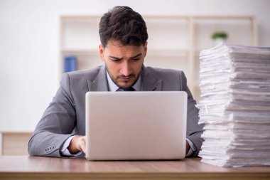 Young employee and too much work at workplace