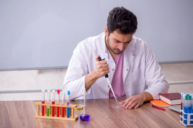 Young chemistry teacher sitting in the classroom