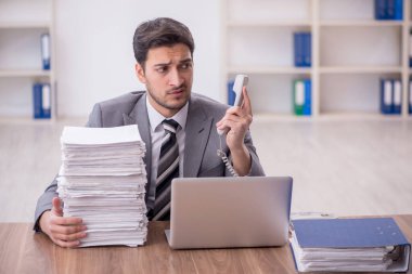 Genç bir çalışan ve ofiste çok fazla iş var.