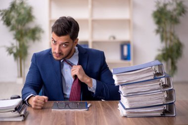 Young employee and too much work at workplace