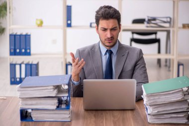 Young employee and too much work at workplace