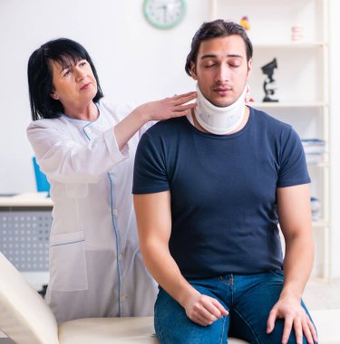 Genç erkek hasta yaşlı kadın doktoru ziyaret ediyor.