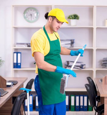 Genç erkek müteahhit ofisi temizliyor.