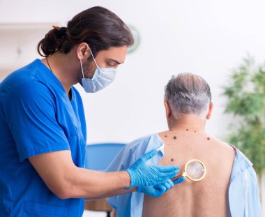 Yaşlı adam erkek doktor dermatoloğunu ziyaret ediyor.