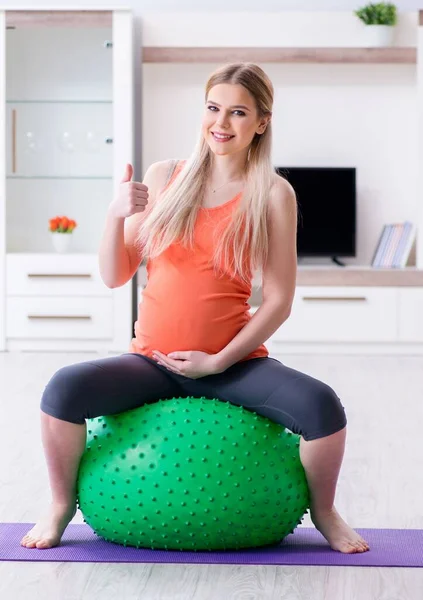 The young woman preparing for birth exercising at home