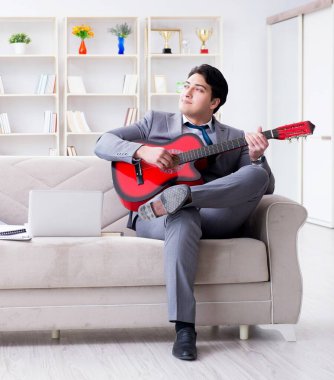 Evde gitar çalan iş adamı.