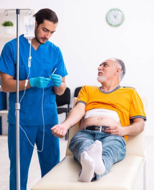 Yaşlı adam erkek doktoru ziyaret ediyor.