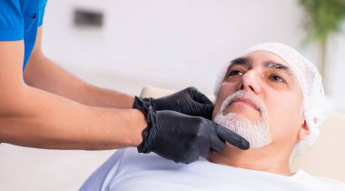 Yaşlı adam estetik ameliyat için doktoru ziyaret ediyor.