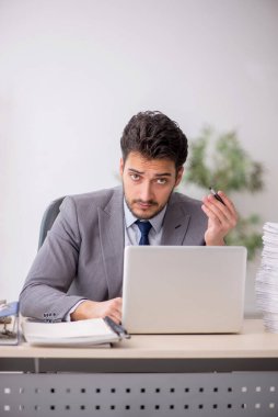 Young employee and too much work at workplace