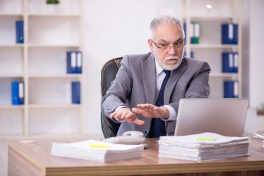 Old businessman employee unhappy with excessive work at workplace